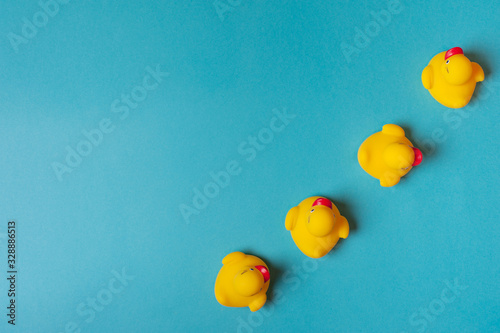 Four yellow rubber ducks on a blue background. Bath concept. Copy space, flat lay.
