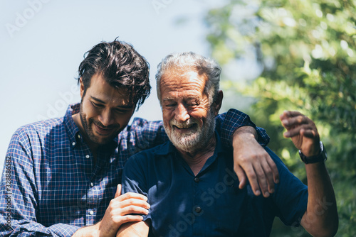 Adult hipster son and old senior father stay for work at home, two generations have a beard talking together and relaxing with smile, happy enjoy living to isolation quarantine at home, father's day photo