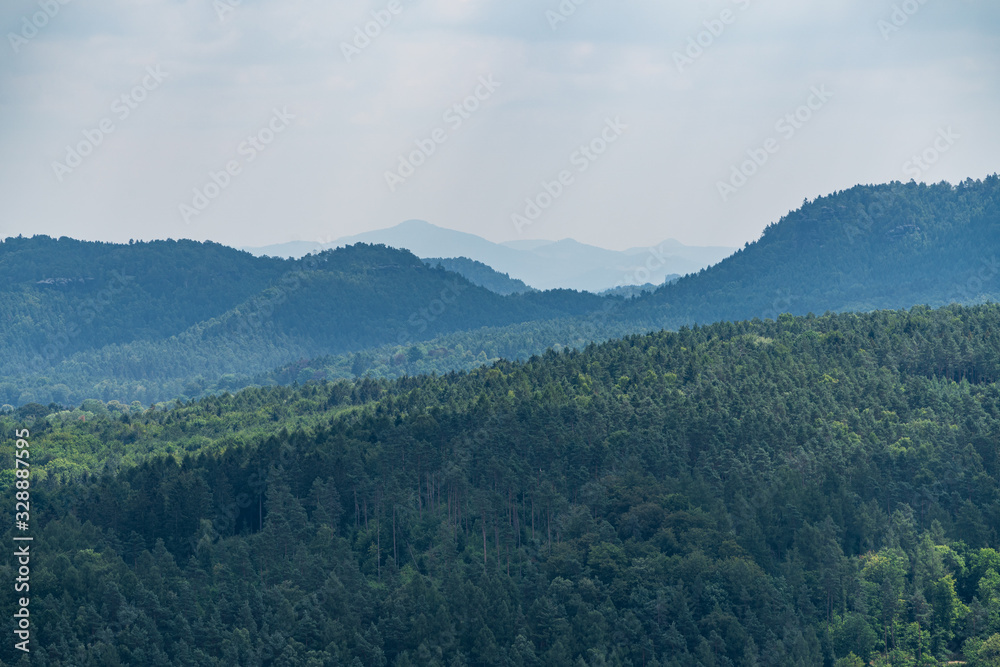 Fototapeta premium Königstein fortress on the banks of the Elbe river, green landscape with mountains in the background. Dresden, Saxon Switzerland, Germany.