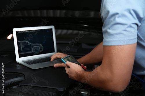 Fototapeta Naklejka Na Ścianę i Meble -  Mechanic with laptop doing car diagnostic at automobile repair shop, closeup