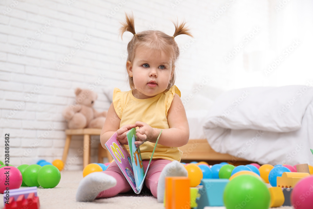 Obraz premium Cute little child with book playing on floor