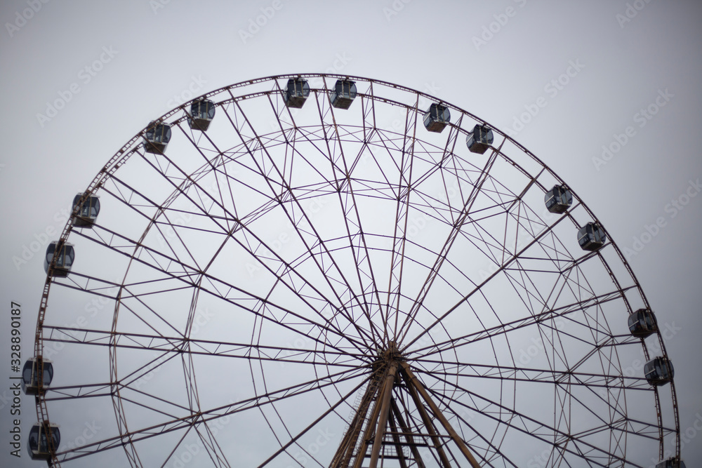 Ferris wheel in the park. City entertainment. Large metal construction. Pleasure vehicle for viewing the cityscape. Attraction for the townspeople. Rest in the park.