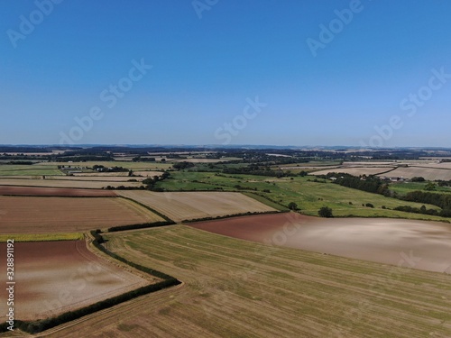 an aerial view of rolling ploughed farmland in the summer