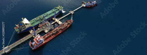Aerial drone ultra wide photo of industrial fuel and gas tanker ship docked in Mediterranean port with deep blue sea