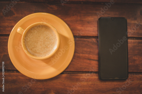 Cup coffee in the table with cellphne photo