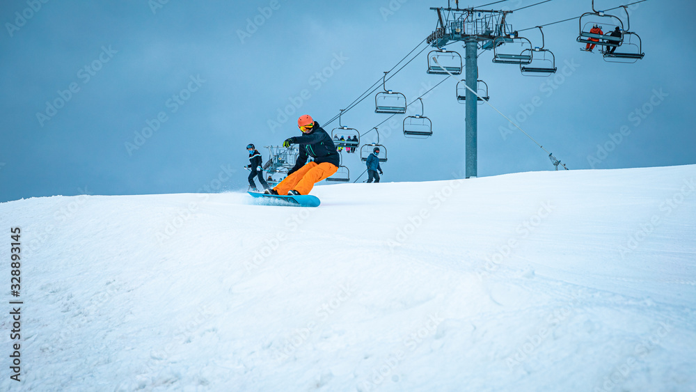 Male teenager taking a turn with his snowboard on a cloudy day