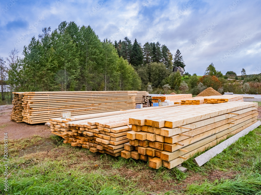 Lumber. Wooden beams lay on the background of the forest. Selling wood for construction. Concept - lumber prepared for construction. House made of wood. Material for the construction of a frame house