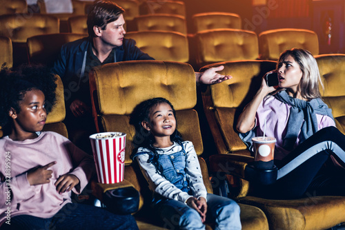 Fotografia Caucasian woman talking on phone in the cinema and showing a rude gesture at the