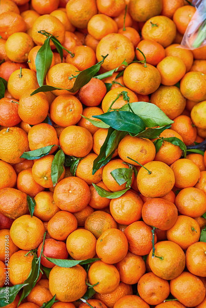 Orange tangerines with leaves lie on a counter in a store top view. Mandarins in the market. Orange tangerines with leaves lie on a counter in a store top view. Mandarins in the market.