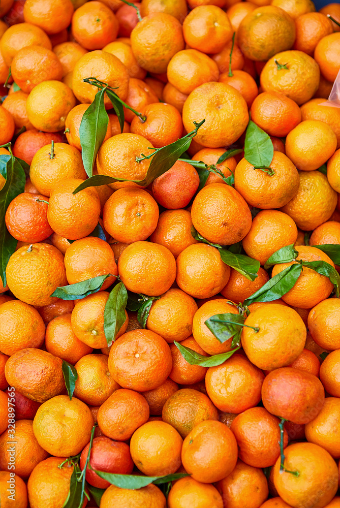 Orange tangerines with leaves lie on a counter in a store top view. Mandarins in the market.