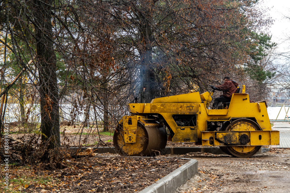 Construction of a new road. Roller for asphalting. Earthwork. Rolling, compaction of gravel. Autumn. Park. Construction of a new road. Roller for asphalting. Earthwork. Rolling, compaction of gravel. Autumn. Park.