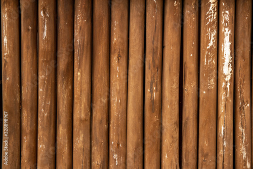 Background of thin brown shabby old wooden logs. Copy space.