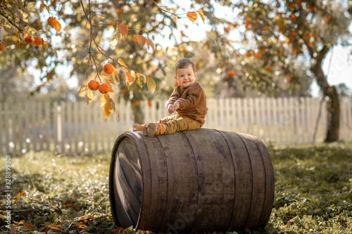 A 3-year-old boy sits on a large wooden barrel.