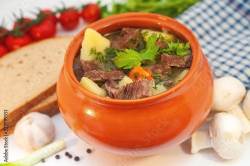 Roast in a pot with beef meat and potatoes on the table