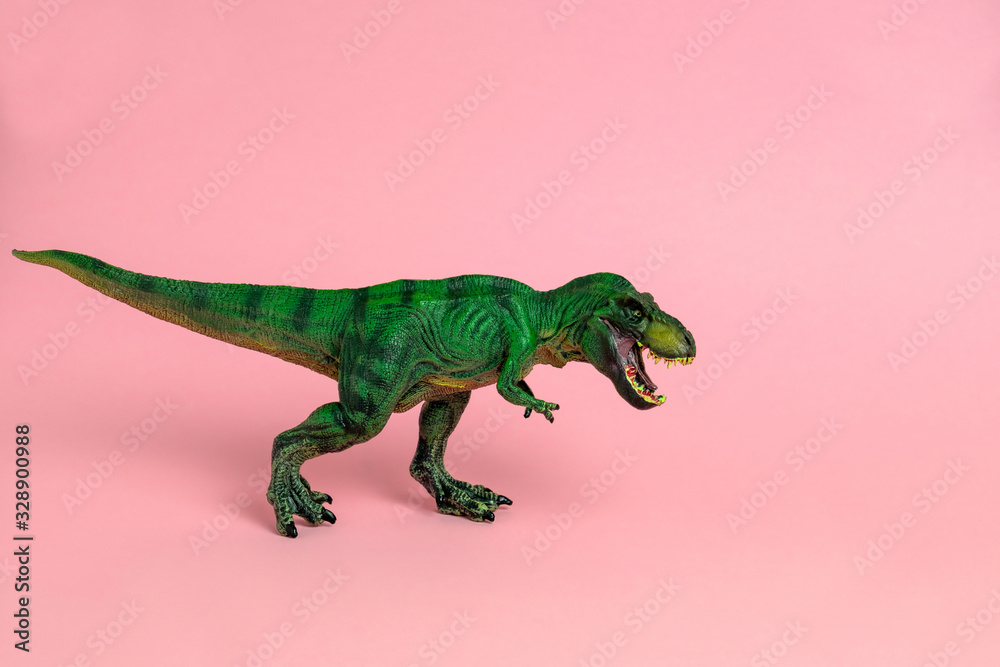 Obraz premium zielona zabawka dinozaura z otwartymi ustami na pastelowym różowym tle