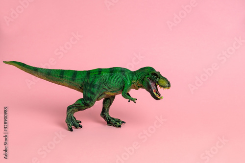 green dinosaur toy with open mouth on a pastel pink  background