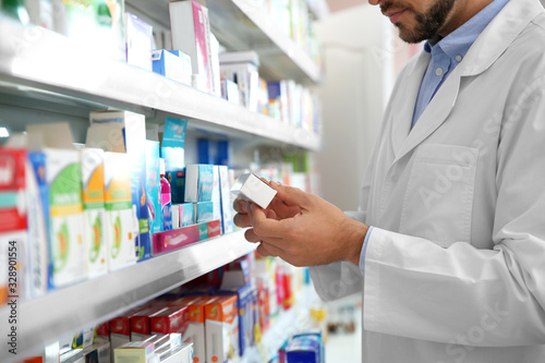 Professional pharmacist with medicine in drugstore, closeup photo