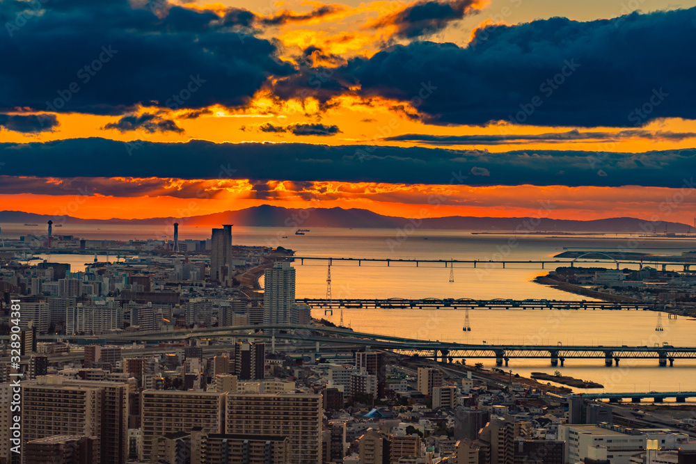Japan. Osaka. Sunset over the of Osaka. Scarlet sunset over the Japanese city. Panorama of Osaka city with red sunset. Automobile bridges over the river in a Japanese city. Japan top view.