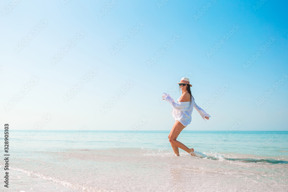 Woman on the beach enjoying summer holidays looking at the sea - obrazy, fototapety, plakaty 