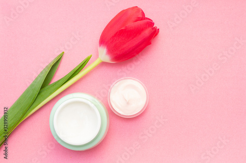 Spring skin care. Tulip and jar of cream on a pink background.