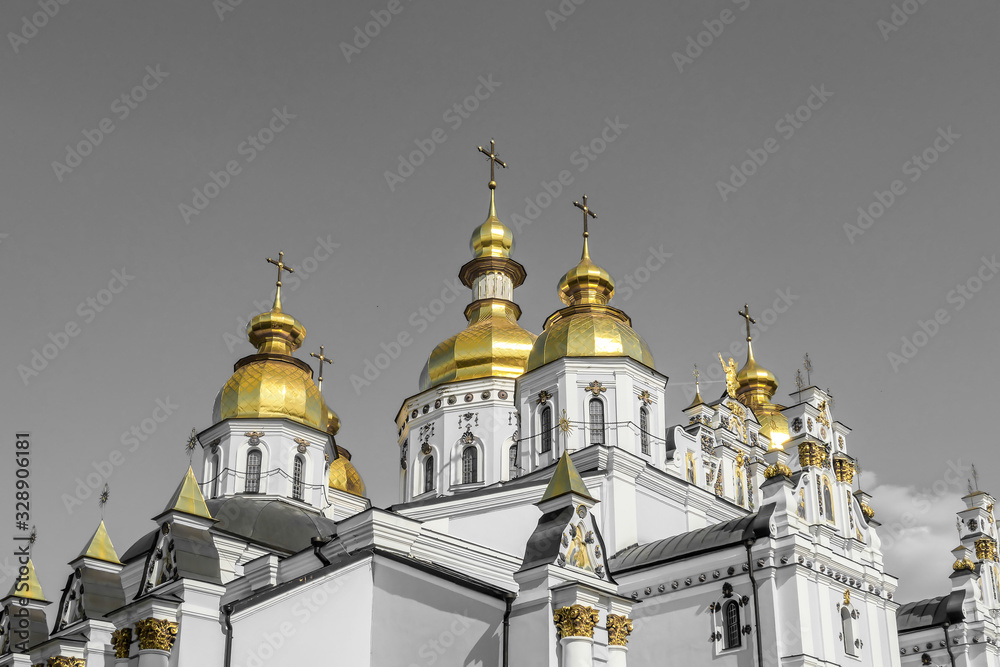 Close-up of the rooftops of St Michael's Golden-Domed Cathedral in Kiev, Ukraine. The walls of the cathedral are painted blue and nicely decorated on each facade. Golden domes reflecting the sun