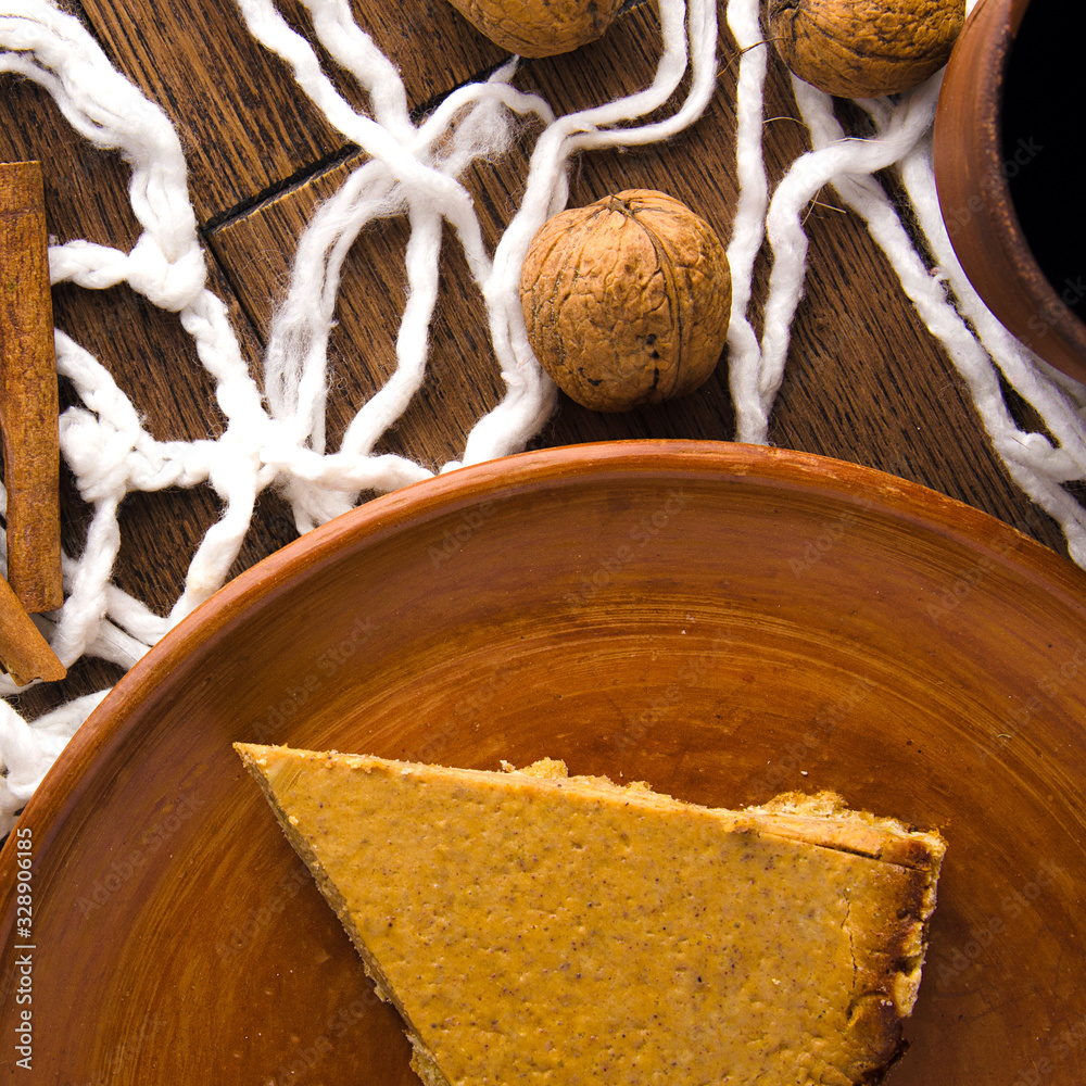 Obraz premium Homemade pumpkin pie with nuts and cinnamon on wooden rustic background top view. cake on a clay plate