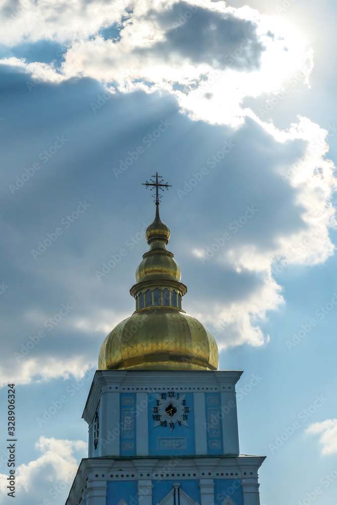 Close-up on the bell tower of St Michael's Golden-Domed Cathedral in Kiev, Ukraine. The walls of the cathedral are painted blue and nicely decorated on each facade. Golden domes reflecting the sun