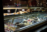 illuminated shop display in an upmarket patisserie in London showing array of cakes and pies
