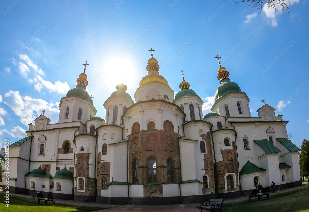 St Sophia's Cathedral in Kiev, Ukraine seen from the front. The cathedral is white with green rooftops and golden turrets. Complex building, consisting of many smaller rooftops and towers.