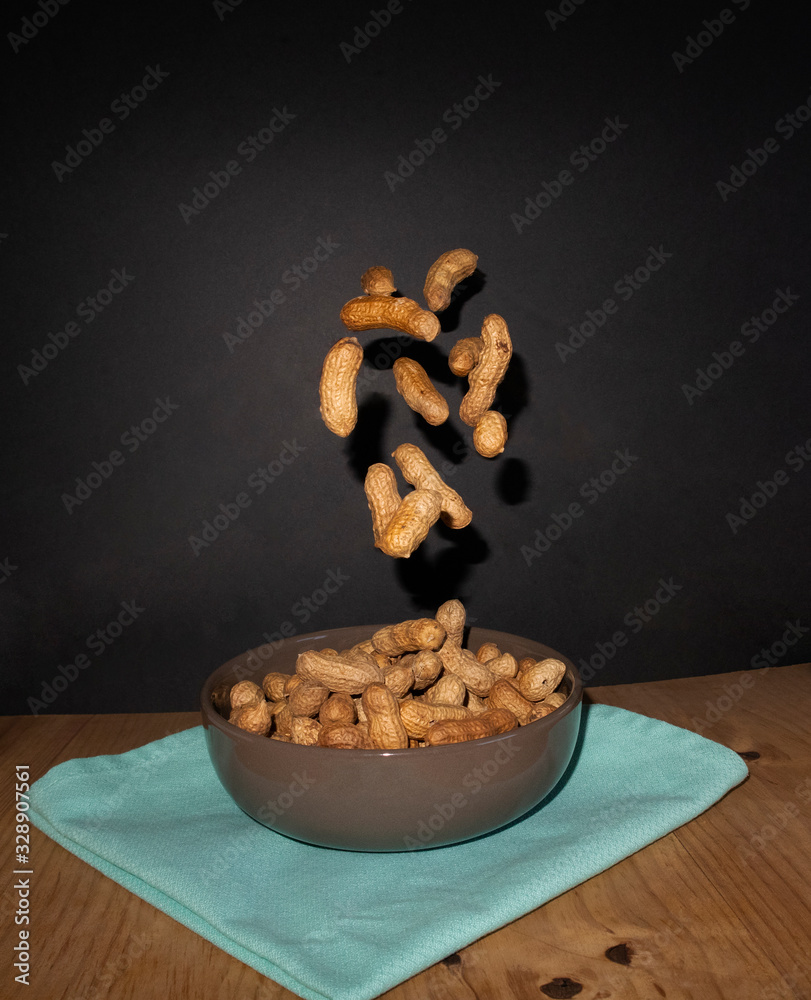 hand drops peanuts in a bowl, instantly where we see the peanuts