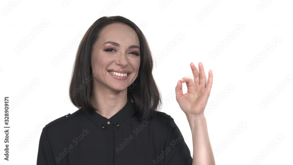 Smiling brunette woman showing ok sign and looking at the camera over white background Smiling brunette woman showing ok sign and looking at the camera over white background