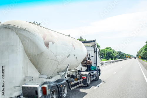 Cement locomotive rides on track, white cement truck carries cement