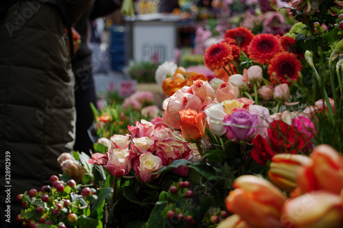 Moody dark tone. Selected focus view at pale orange  pink and white bouquet of blooming roses in front of floral shop in outdoor market in Europe. Typical atmosphere of flower store.   