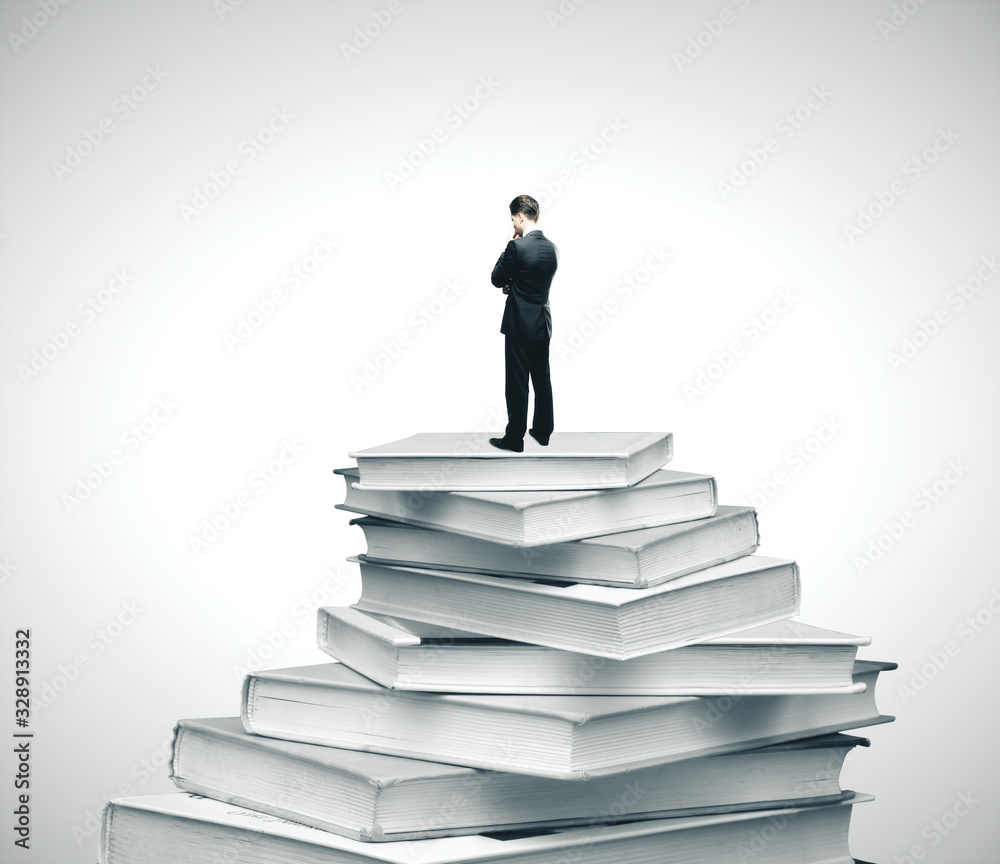 Businessman standing on pile of books Businessman standing on pile of books