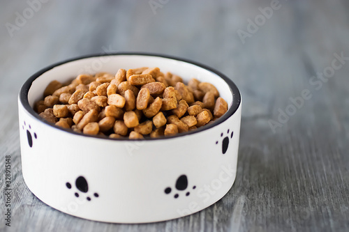 Fototapeta Naklejka Na Ścianę i Meble -  Dry cat food in a white bowl on gray background.