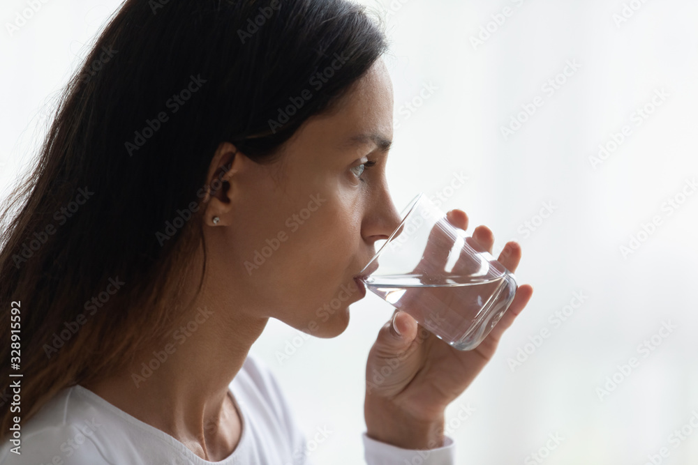 Side view of young Caucasian woman drinking pure water from glass follow healthy lifestyle, having good habits, millennial girl feel thirsty enjoy clear mineral still aqua, maintain body balance Side view of young Caucasian woman drinking pure water from glass follow healthy lifestyle, having good habits, millennial girl feel thirsty enjoy clear mineral still aqua, maintain body balance