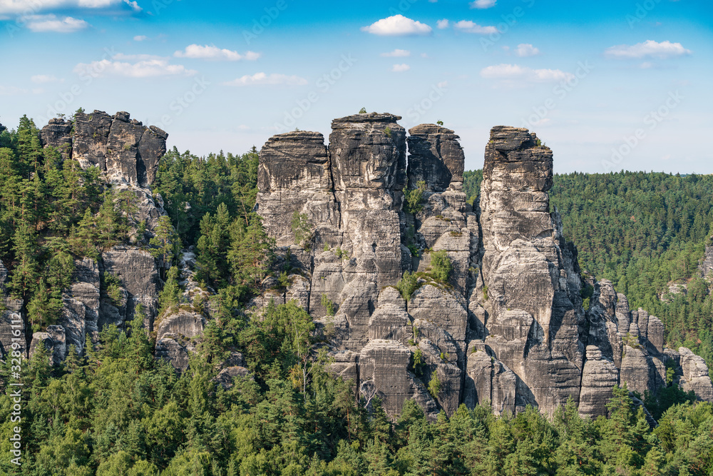 Bad Schandau in Bohemian Switzerland. Bastei bridge and mountain view. Narrow rock, natural sandstone arch in Europe..Hill scenery with greenery, blue sky and sunlight.