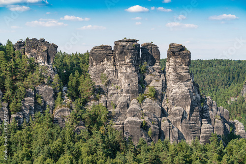 Bad Schandau in Bohemian Switzerland. Bastei bridge and mountain view. Narrow rock  natural sandstone arch in Europe..Hill scenery with greenery  blue sky and sunlight.