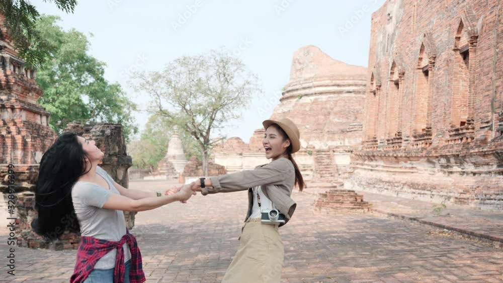 Asian Two Young Women excited Holding Hands and Spinning together. She is enjoying in world heritage city Ayutthaya Thailand. Woman having fun, traveling on holidays The old town. Slow Motion Asian Two Young Women excited Holding Hands and Spinning together. She is enjoying in world heritage city Ayutthaya Thailand. Woman having fun, traveling on holidays The old town. Slow Motion