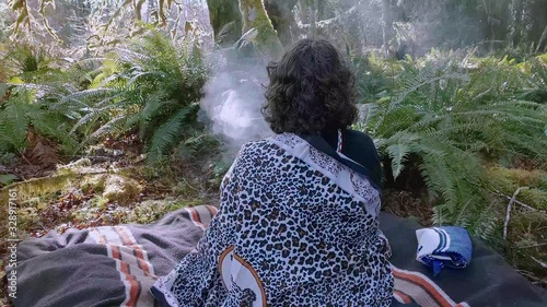 Woman shaman praying and burning plant medicine for her ancestors, meditate