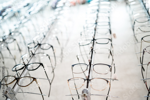 Exhibition of glasses at shelves. Fashionable spectacles shown on a wall at the optical shop. Closeup. photo