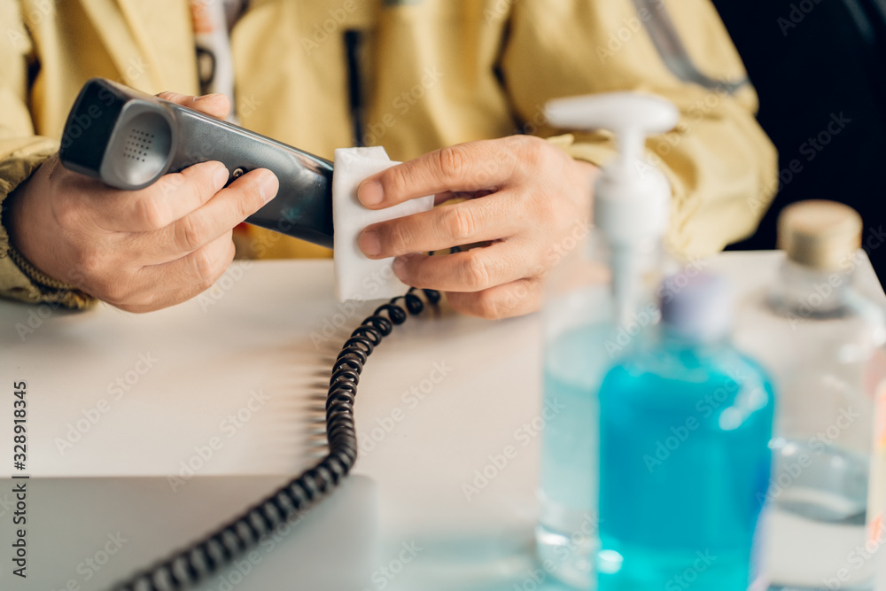 Man Cleaning a mouthpiece of the telephone handset with alcohol pad.Hygiene concept. prevent the spread of germs and bacteria and avoid infections corona virus or covid19 Man Cleaning a mouthpiece of the telephone handset with alcohol pad.Hygiene concept. prevent the spread of germs and bacteria and avoid infections corona virus or covid19