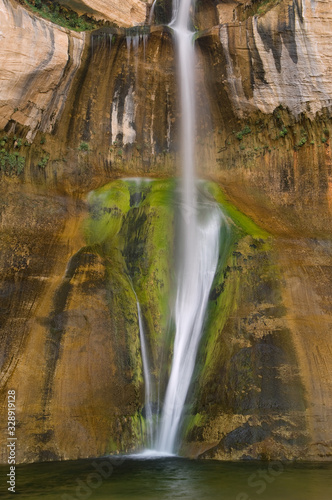 Calf Creek Falls captured with motion blur  cascades over mineral stained  sandstone cliff  Utah  USA