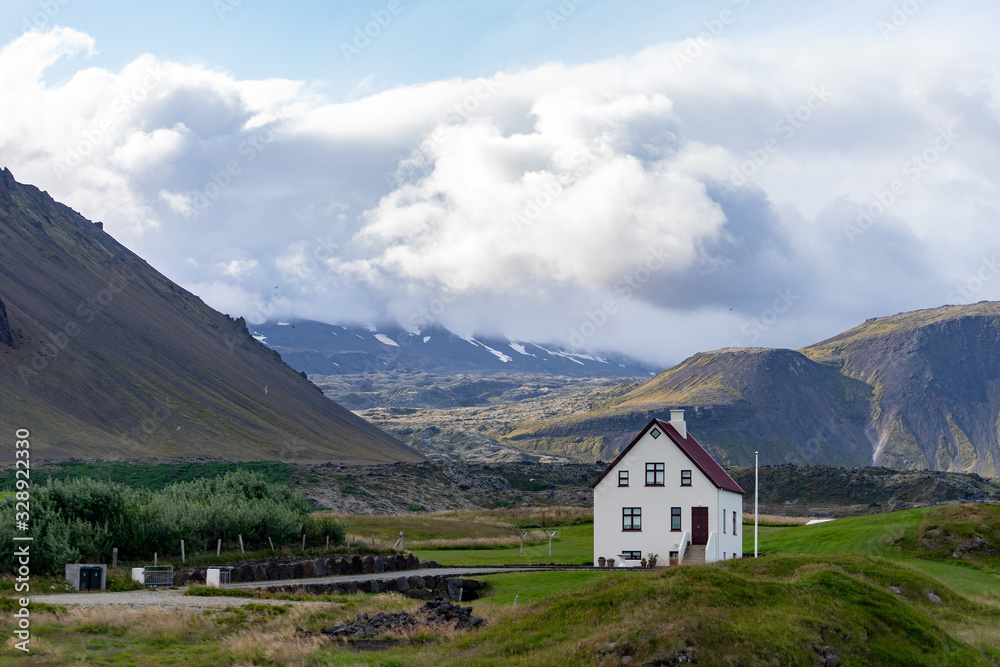 Farmhouse on hill in Iceland with cloudy sky and nice view on background 