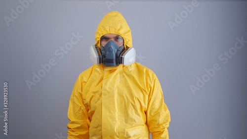A man in a chemical protection suit on a gray background. photo
