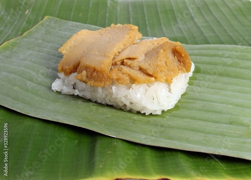 Thai dessert, steamed sticky rice, custard wrapped in banana leaves.
