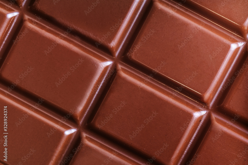A bar of milk chocolate closeup. The concept of sweets, junk food. Detailed texture macro photo in warm colors. A bar of milk chocolate closeup. The concept of sweets, junk food. Detailed texture macro photo in warm colors.