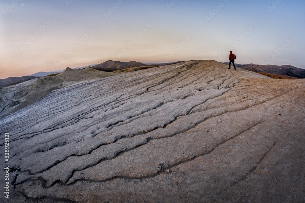 Young man walking in a lunar landscape over the muddy volcanoes, Paclele, Berca, Buzau County, Romania