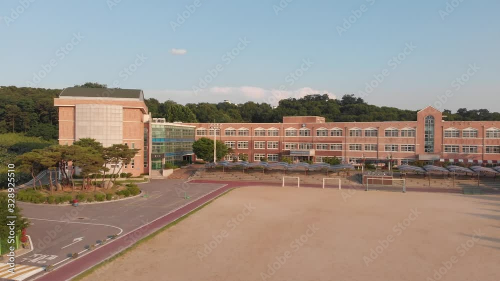 Rising aerial shot of modern school building in South Korea surrounded by forest at sunset. Pedestal Rising aerial shot of modern school building in South Korea surrounded by forest at sunset. Pedestal