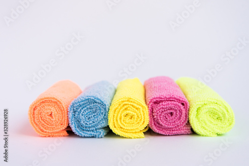Multicolored microfiber cloths, folded into rollers. The fabrics are laid out in a row.